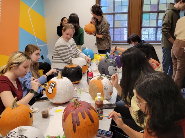 Student paint pumpkins at a fall event